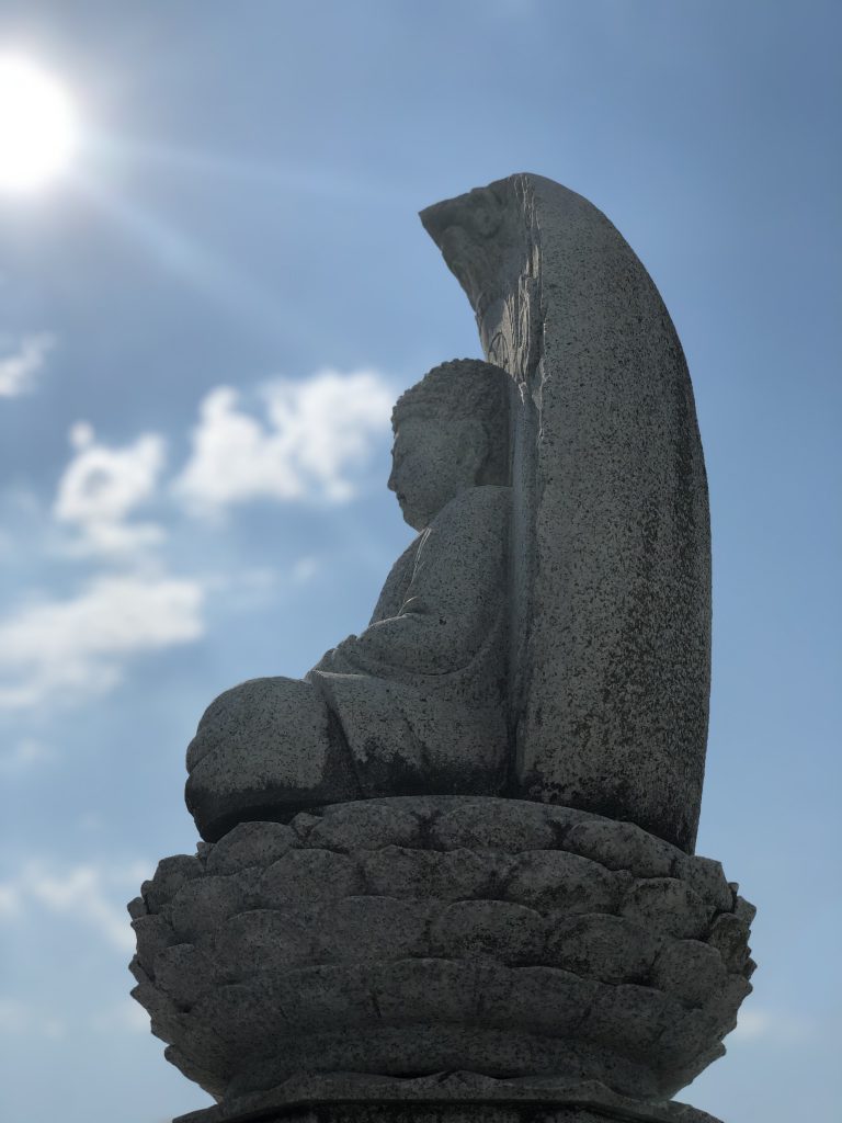 陽に照らされる能満寺の永代供養塔の石仏(山梨県甲府市)